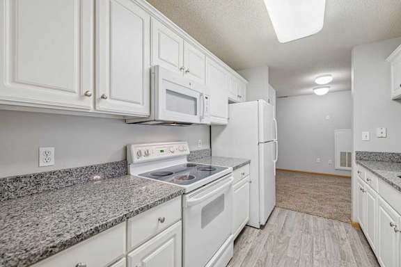 A kitchen with white cabinets and appliances.