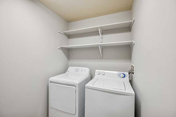 Two white front loading washing machines in a small laundry room.