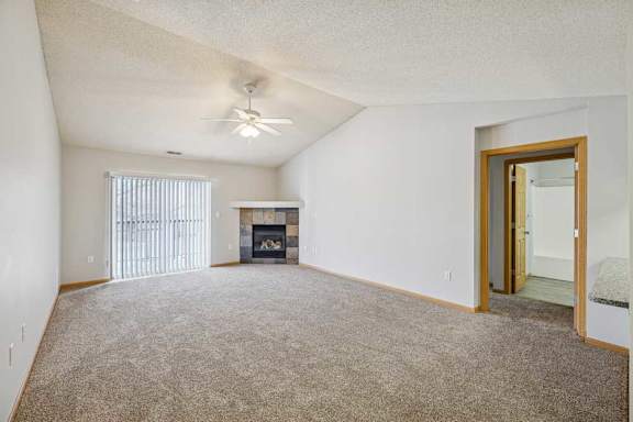 A spacious living room with a fireplace and a ceiling fan.