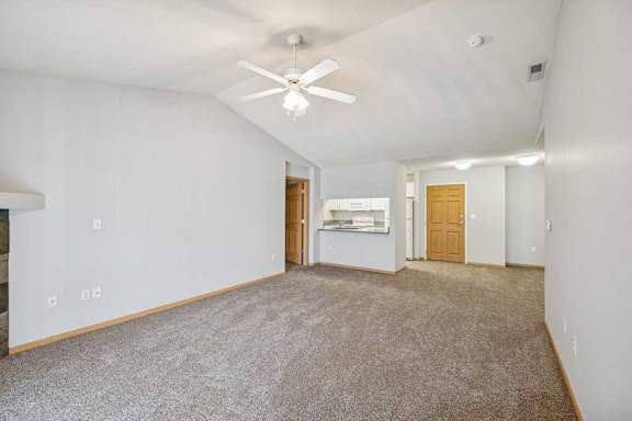 A spacious room with a ceiling fan and carpeted floor.