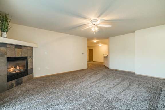 A living room with a fireplace and a grey carpet.