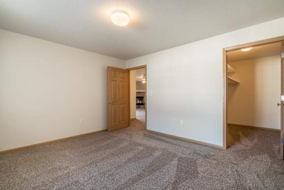 A room with a carpeted floor and a door leading to another room.