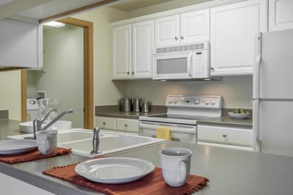 A kitchen with white cabinets and a white fridge.
