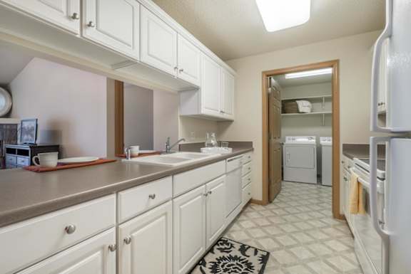 A kitchen with white cabinets and a black and white rug on the floor.