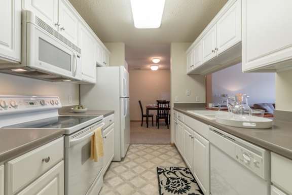 A kitchen with white appliances and cabinets.
