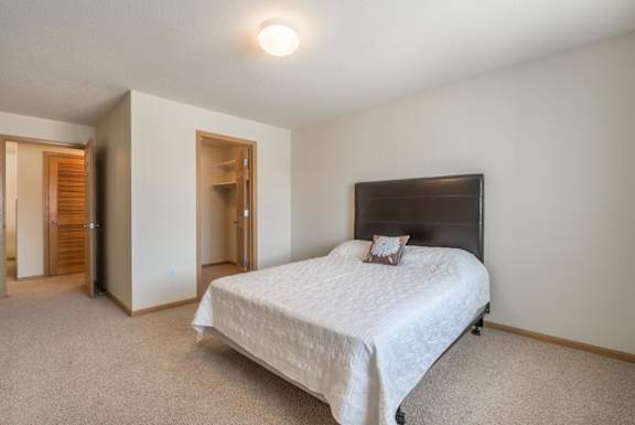 A bedroom with a bed, carpet, and a door.