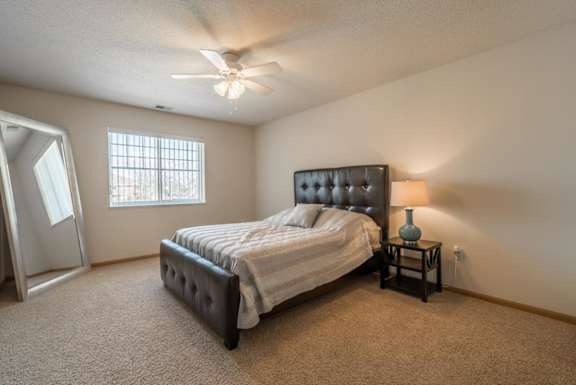 A bedroom with a bed, a nightstand, and a ceiling fan.