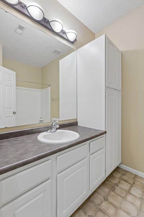 A bathroom with a sink, mirror, and cabinets.