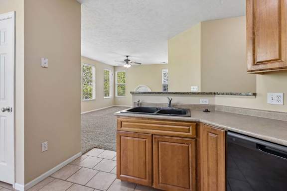 A kitchen with wooden cabinets and a black dishwasher.