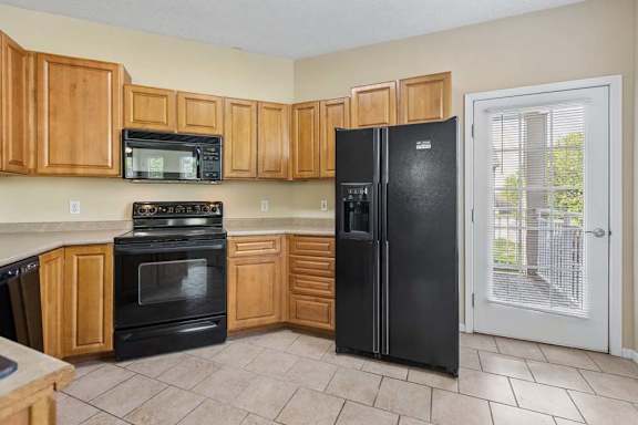 A kitchen with black appliances and wooden cabinets.