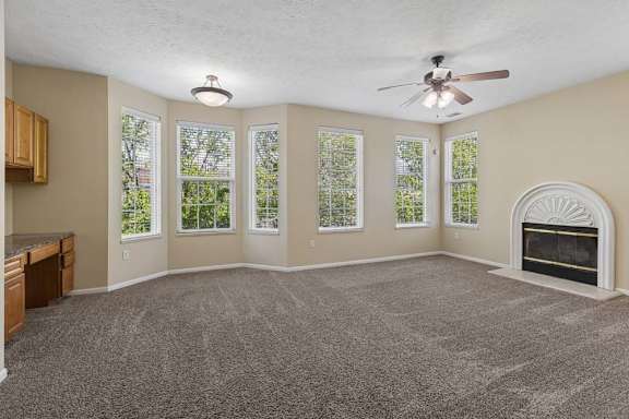 A spacious living room with a fireplace and a ceiling fan.