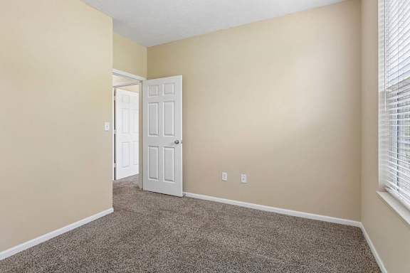A room with a carpeted floor and a white door.