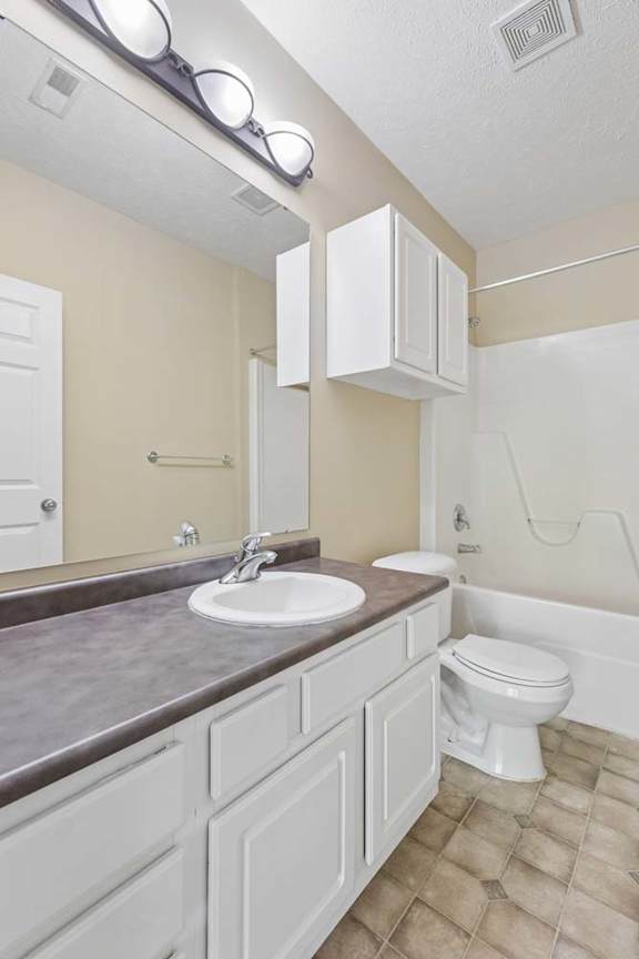 A bathroom with a sink, toilet, and a mirror.