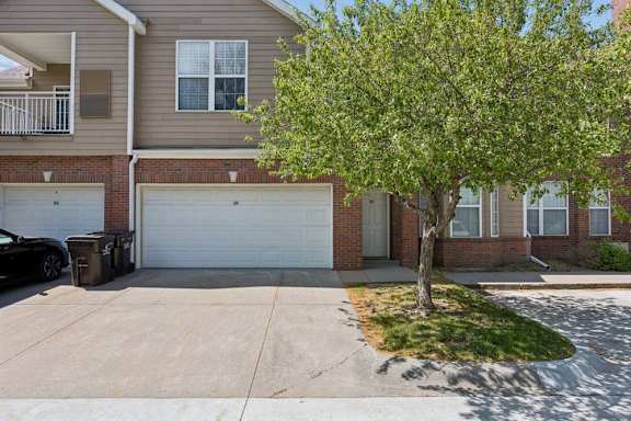 A tree is in front of a house with a garage door.