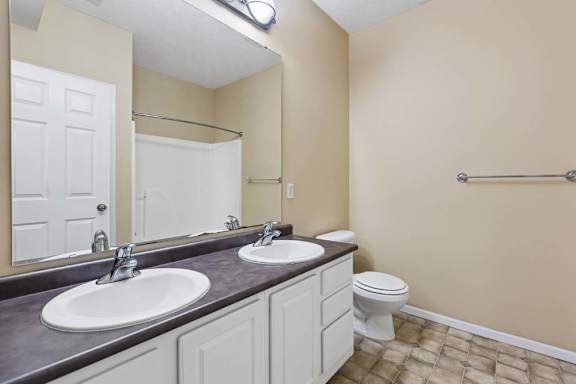 A bathroom with a toilet, sink, and mirror.
