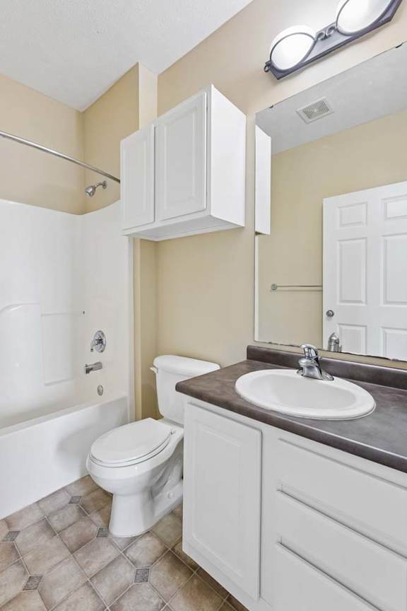 A white toilet sits in a bathroom next to a sink.