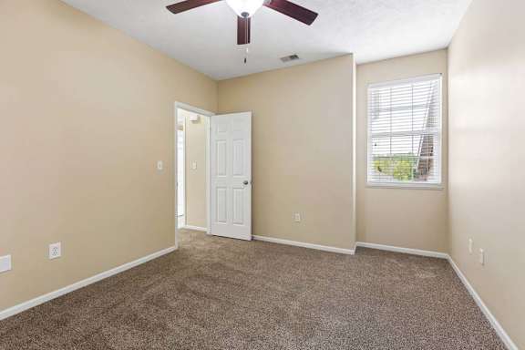 A room with a ceiling fan and a window with blinds.