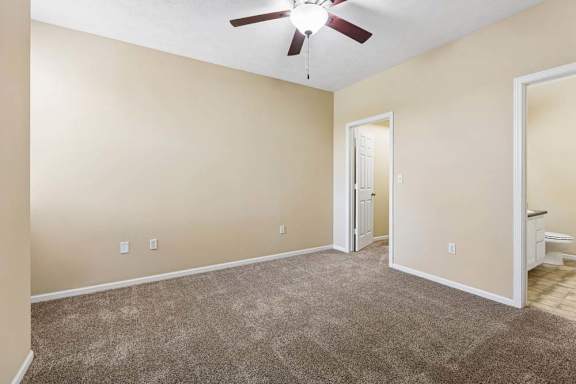 A room with a ceiling fan and carpeted floor.