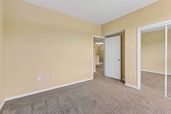 A room with a carpeted floor and a white door.