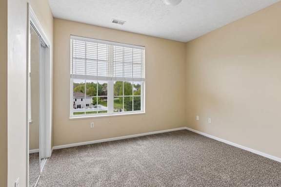 A room with a large window and a carpeted floor.