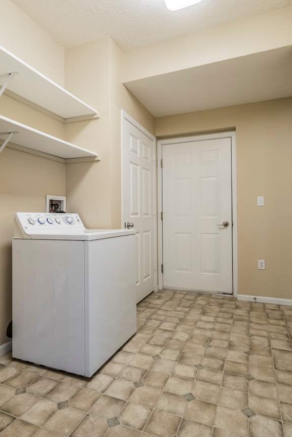 A white washing machine in a room with a door and a wall.