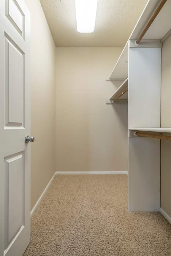 A white door is on the left of a hallway with a carpeted floor.