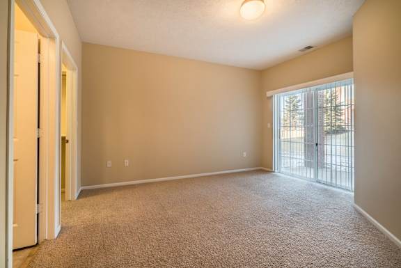 A room with carpeted floor and sliding glass doors.