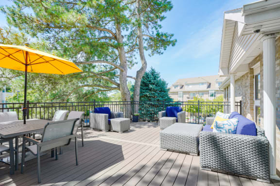 Sun deck with outdoor furniture and table and chairs shaded by a yellow umbrella