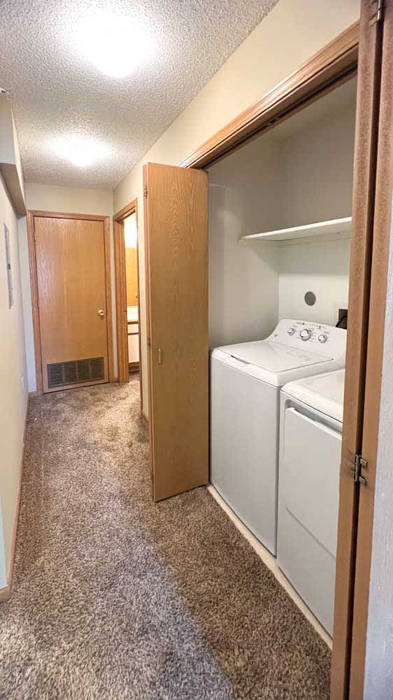 a hallway with a laundry closet with a full sized washer and dryer