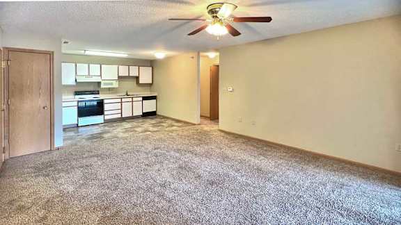 a living room with a carpeted floor and a ceiling fan