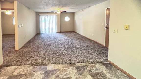 a living room with a carpeted floor and a ceiling fan