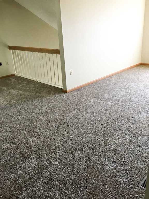 a loft area with carpeted flooring and a railing