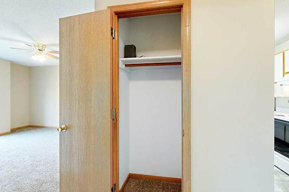 Coat closet with hanging rod and upper shelf, located off the main living area.