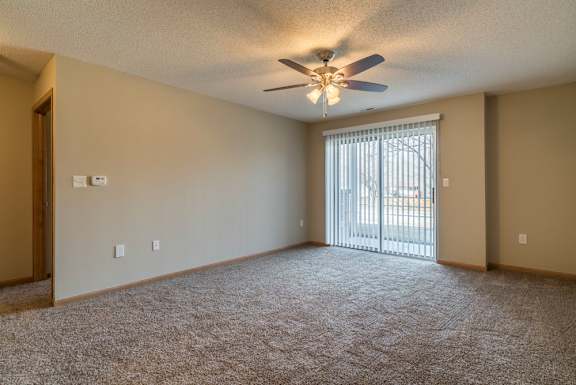 A room with a ceiling fan and carpeted floor.