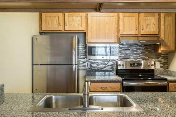 A kitchen with a stainless steel refrigerator, microwave, oven, and sink.