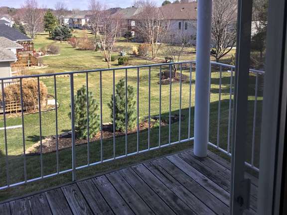 a view from a balcony overlooking a green lawn and trees