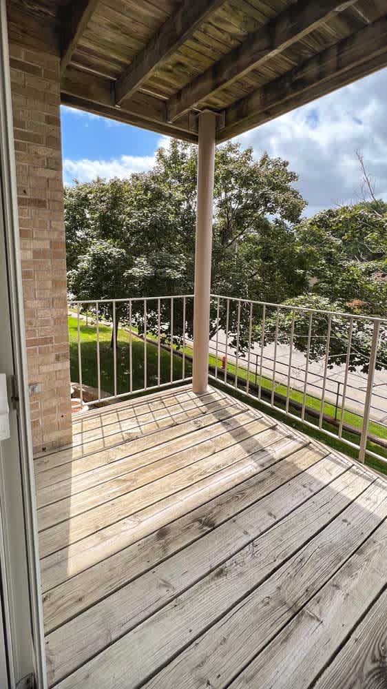 a wooden balcony deck with a metal railing