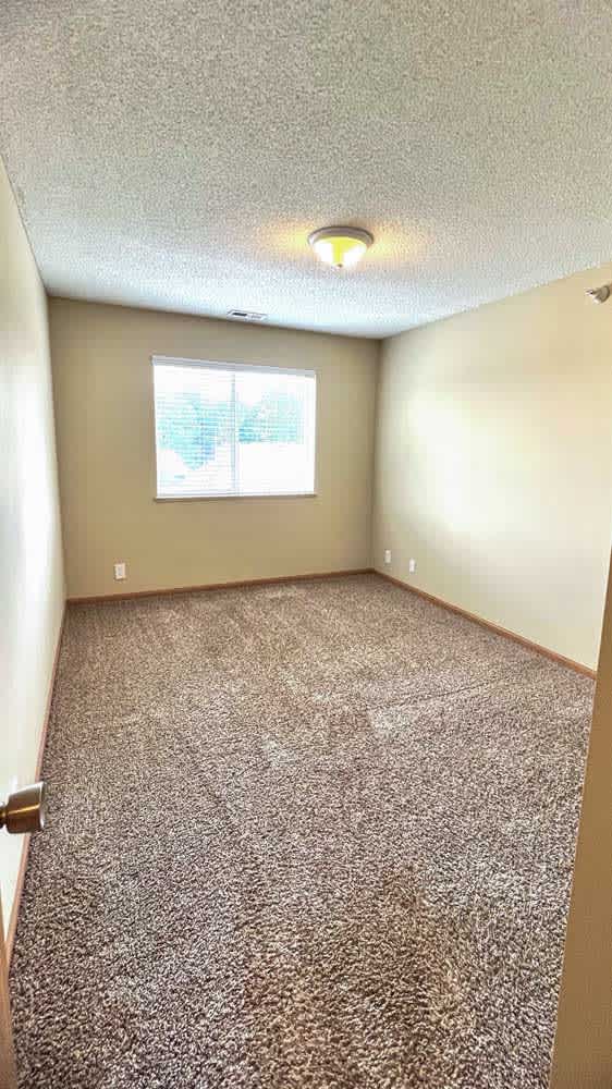 a bedroom with a window and a carpeted floor