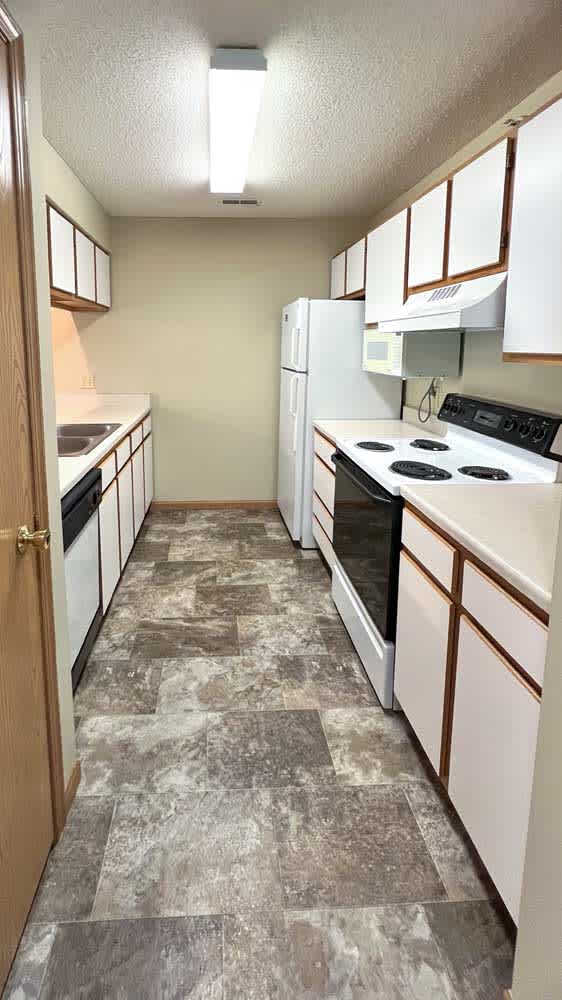 a kitchen with a vinyl tiled floor and white and brown cabinets