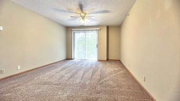 a living room with a carpeted floor and a ceiling fan
