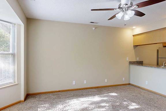 Carpeted living room with large window, breakfast bar, and open layout connecting to the kitchen.