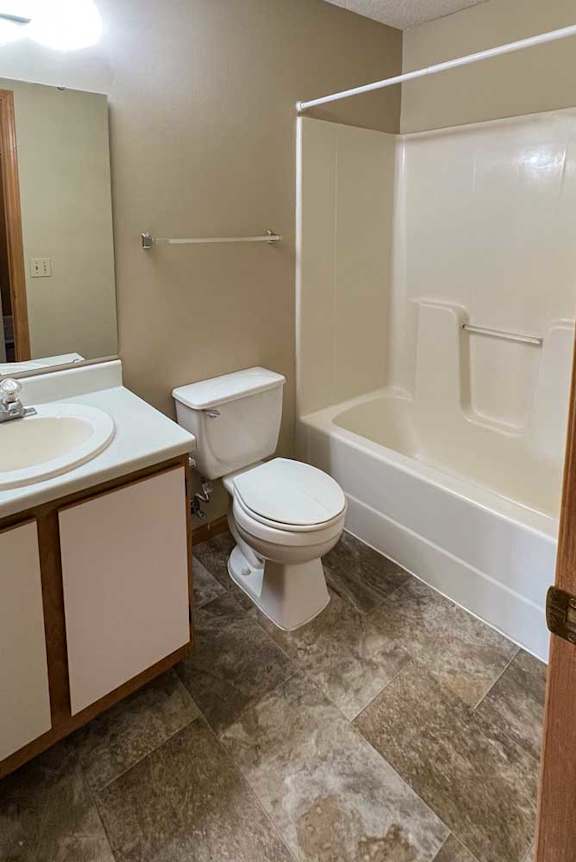 a bathroom with a vanity sink, a towel rack, and a tub shower