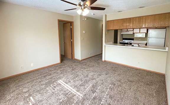 a living room with a ceiling fan and carpeted flooring