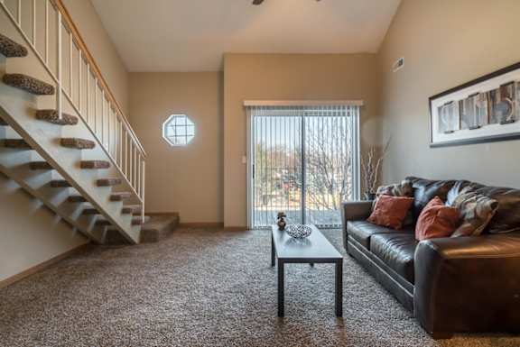 A living room with a couch, coffee table, and staircase.
