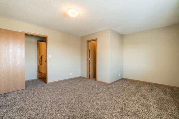 A room with carpeted floor and two doors.