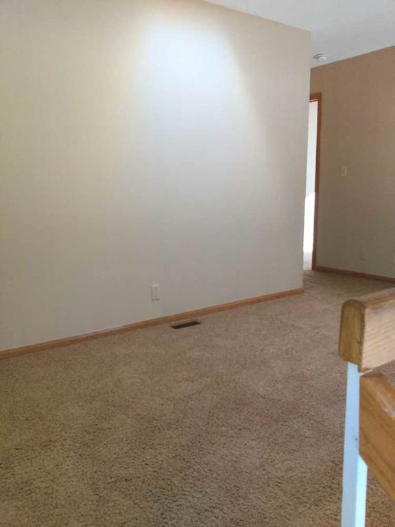 a carpeted loft area with a small hallway leading to a bedroom and bathroom