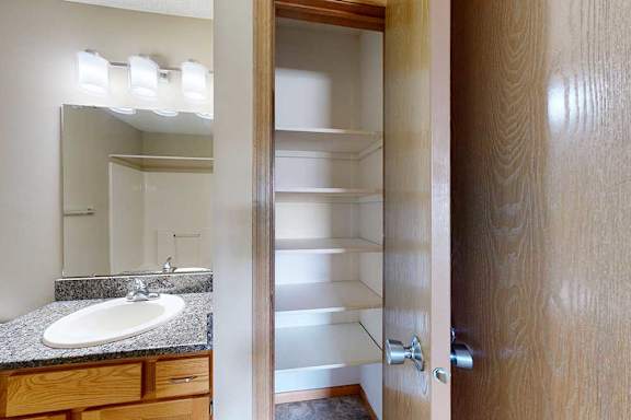 Linen closet with built-in shelving for organized storage, located next to the bathroom vanity.