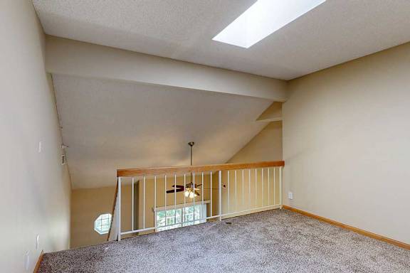 Loft space with angled ceiling, skylight, and open railing overlooking the main living area.