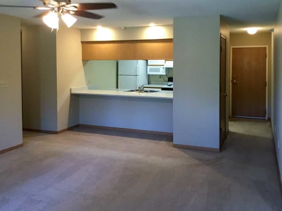 a living room with a ceiling fan and kitchen with a windowed countertop