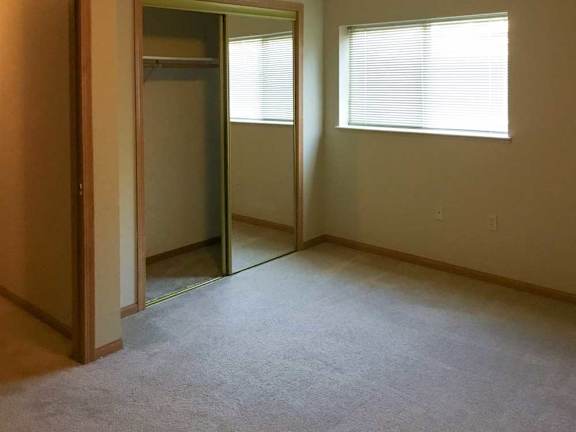 a bedroom with a carpeted floor and a window with blinds